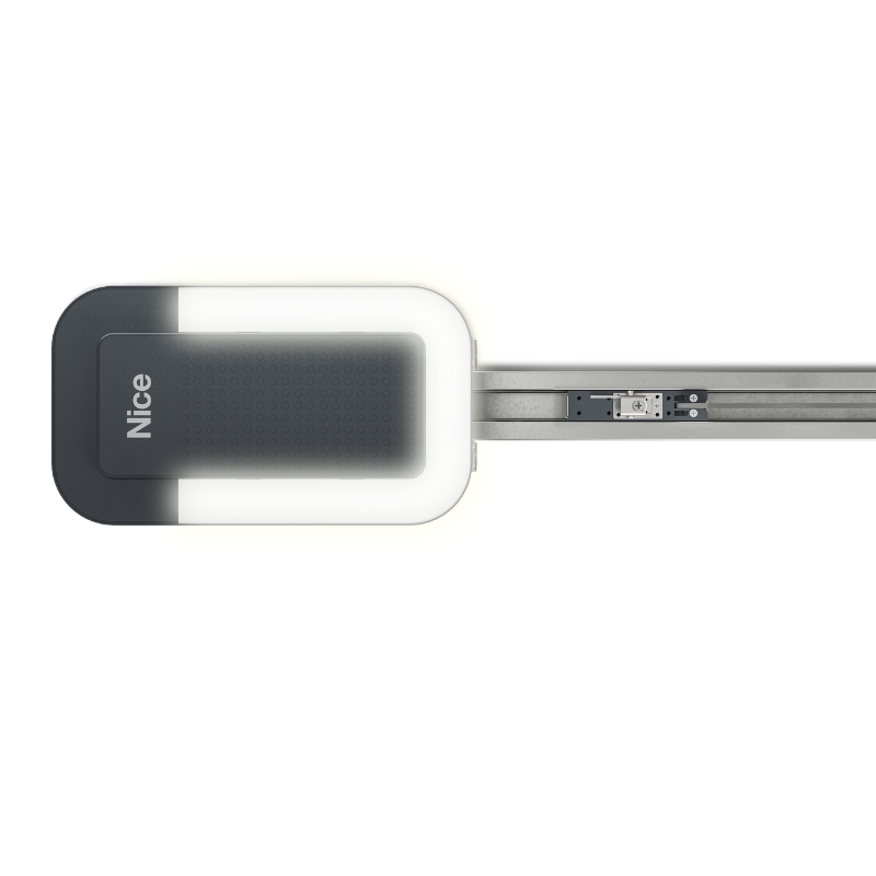 Na czwartym zdjęciu widziana jest obudowa silnika systemu do automatycznego otwierania drzwi rolowanych w kolorze czarno-białym, której białe obramowanie jest podświetlone LED, a po prawej stronie rozciąga się metalowa szyna z zamontowanym mechanizmem jezdnym.