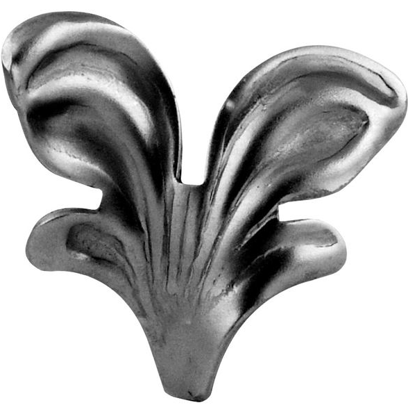 Na zdjęciu znajduje się metalowy element ozdobny w kształcie stylizowanego liścia lub płomienia, o trzech wyraźnych, wypukłych segmentach. Element ma powierzchnię z widocznymi przetarciami i teksturą charakterystyczną dla odlewu metalowego.